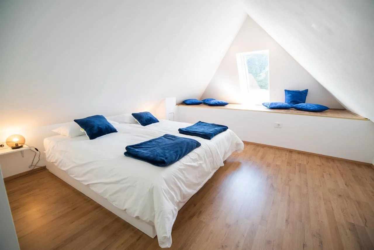 Zakonska postelja pod poševnim stropom v mansardi apartmaja 1