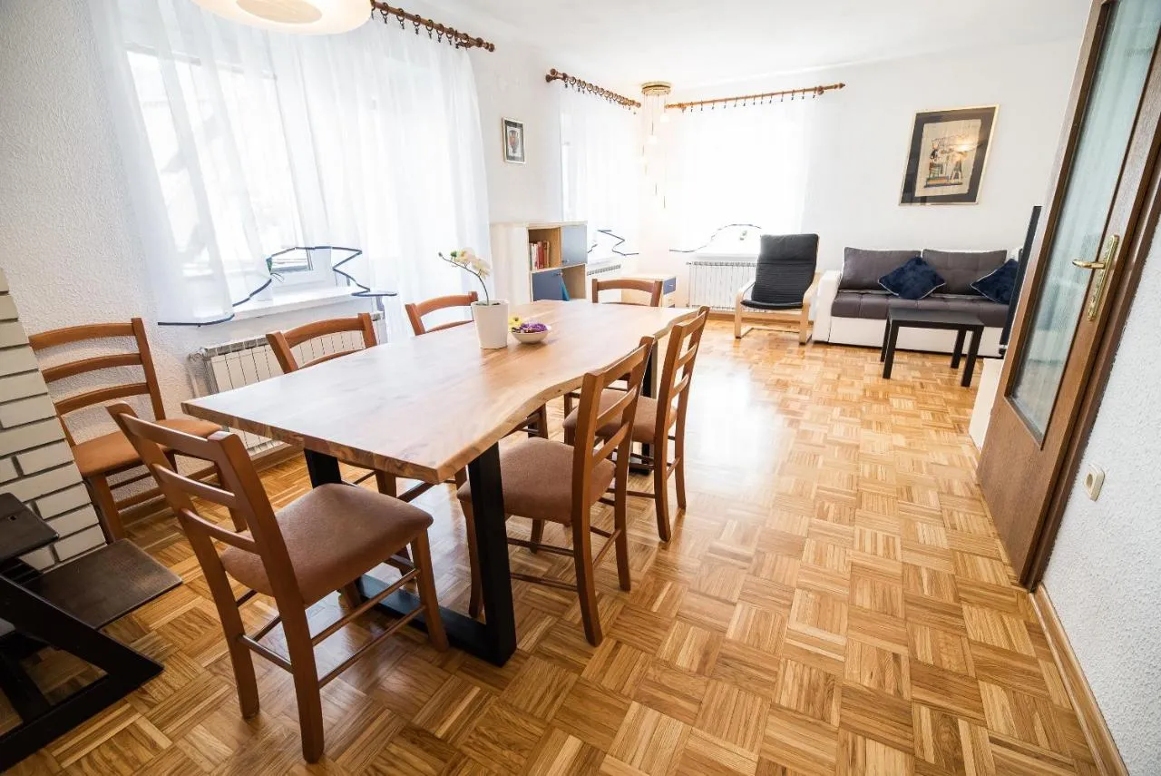 Dnevni prostor apartmaja 3 z dolgo leseno mizo in sedežno garnituro